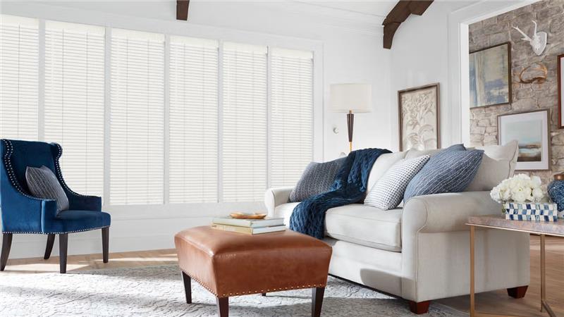 white couch in a  living room in front of white blinds on window